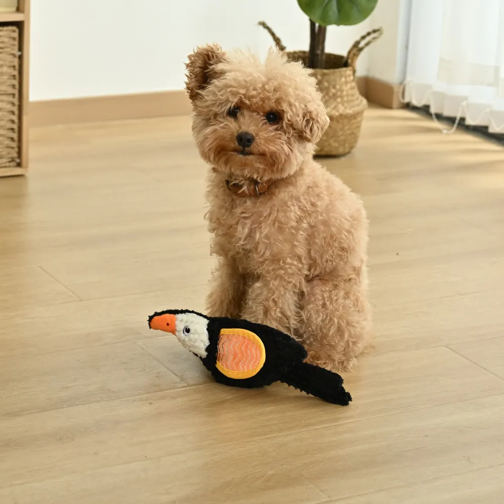 small puppy sitting with plush bird squeaky dog toy indoor pet play scene