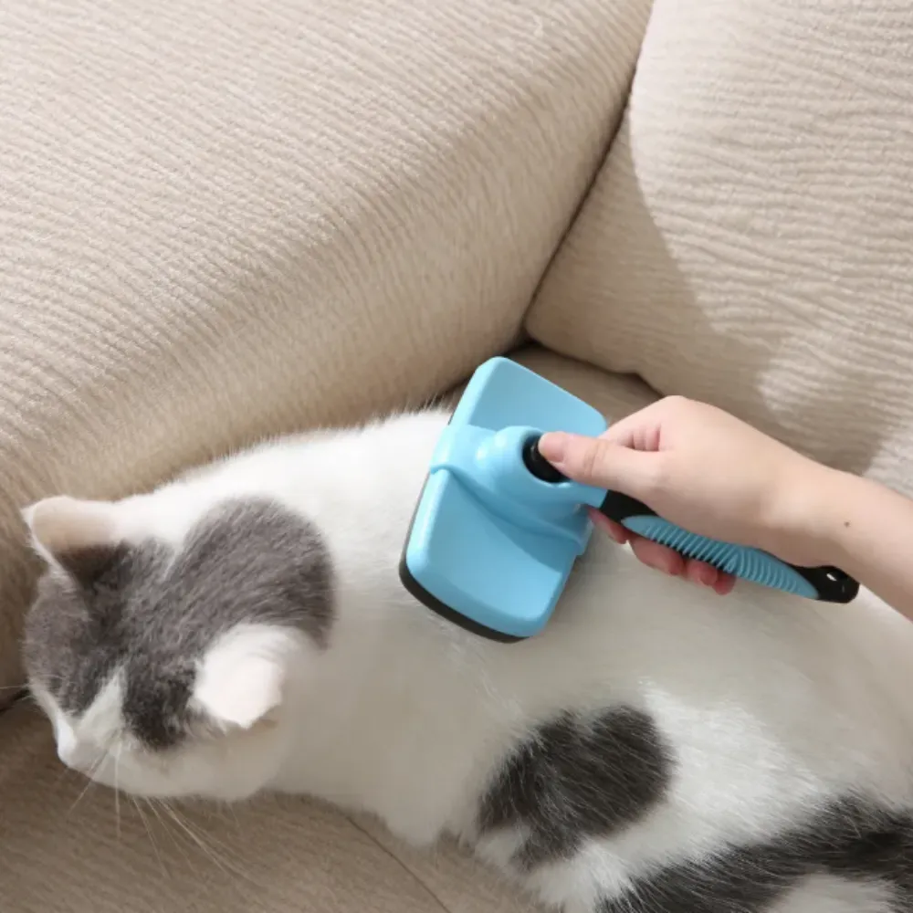 Close-up of a blue grooming brush being used on a cat, highlighting the ergonomic non-slip handle.