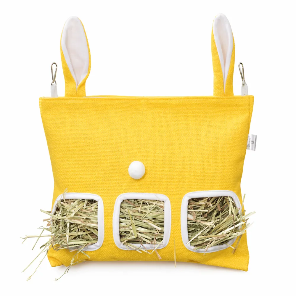 A bright yellow bunny-shaped hay feeder bag filled with fresh hay, featuring white bunny ear details.