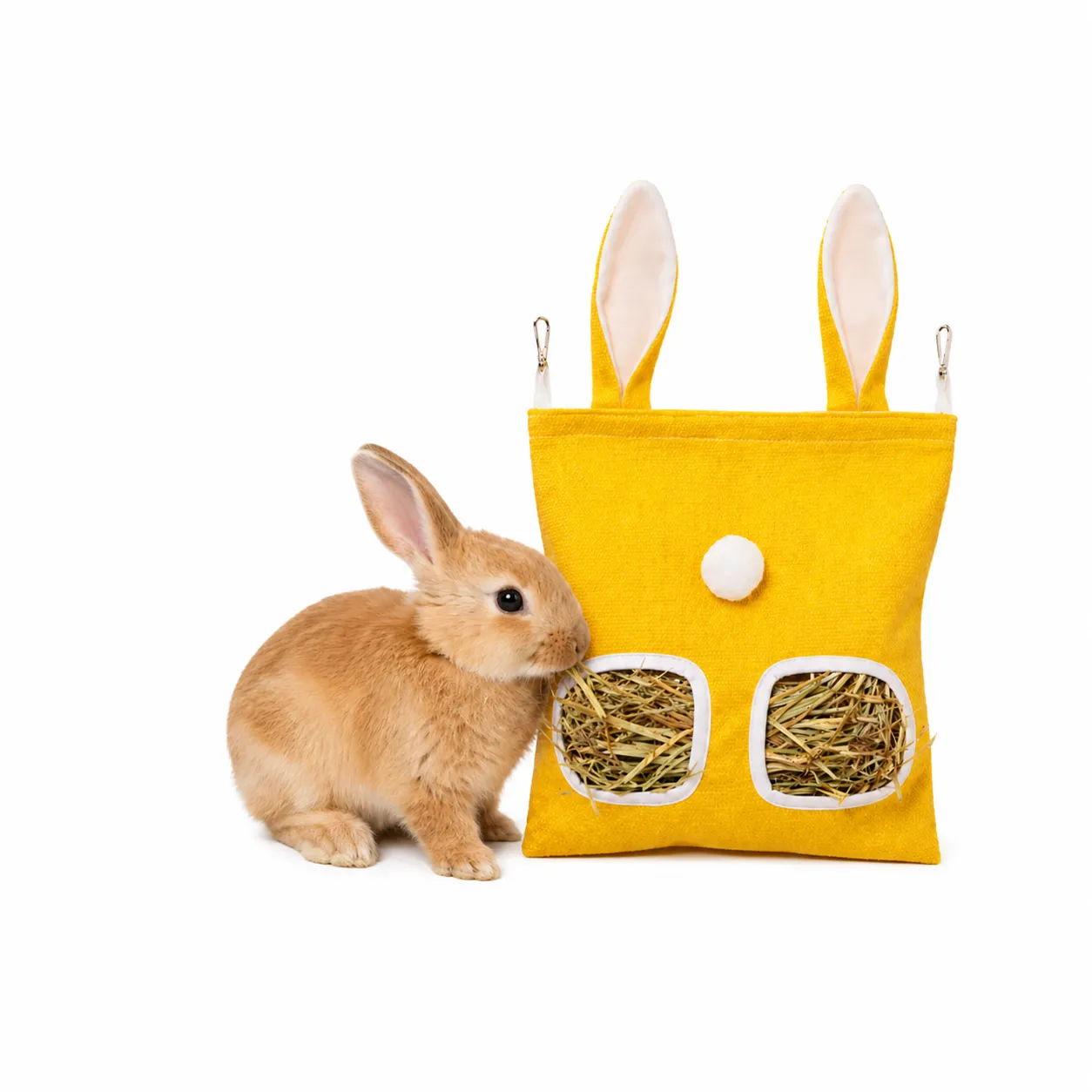 Cute bunny eating hay from yellow hanging rabbit hay feeder bag interactive foraging toy for small pets