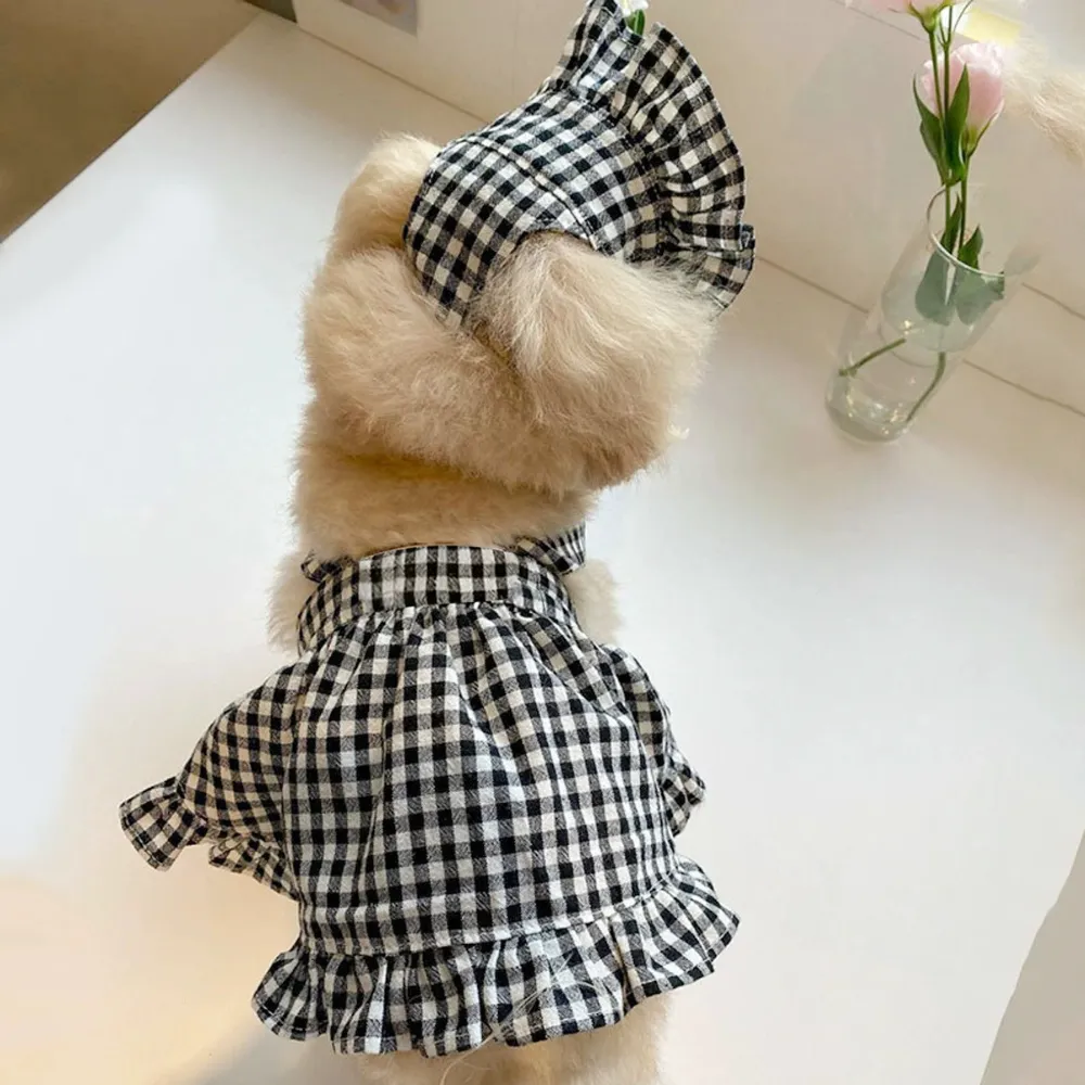 Rear view of small dog wearing a black plaid pet dress and matching bonnet