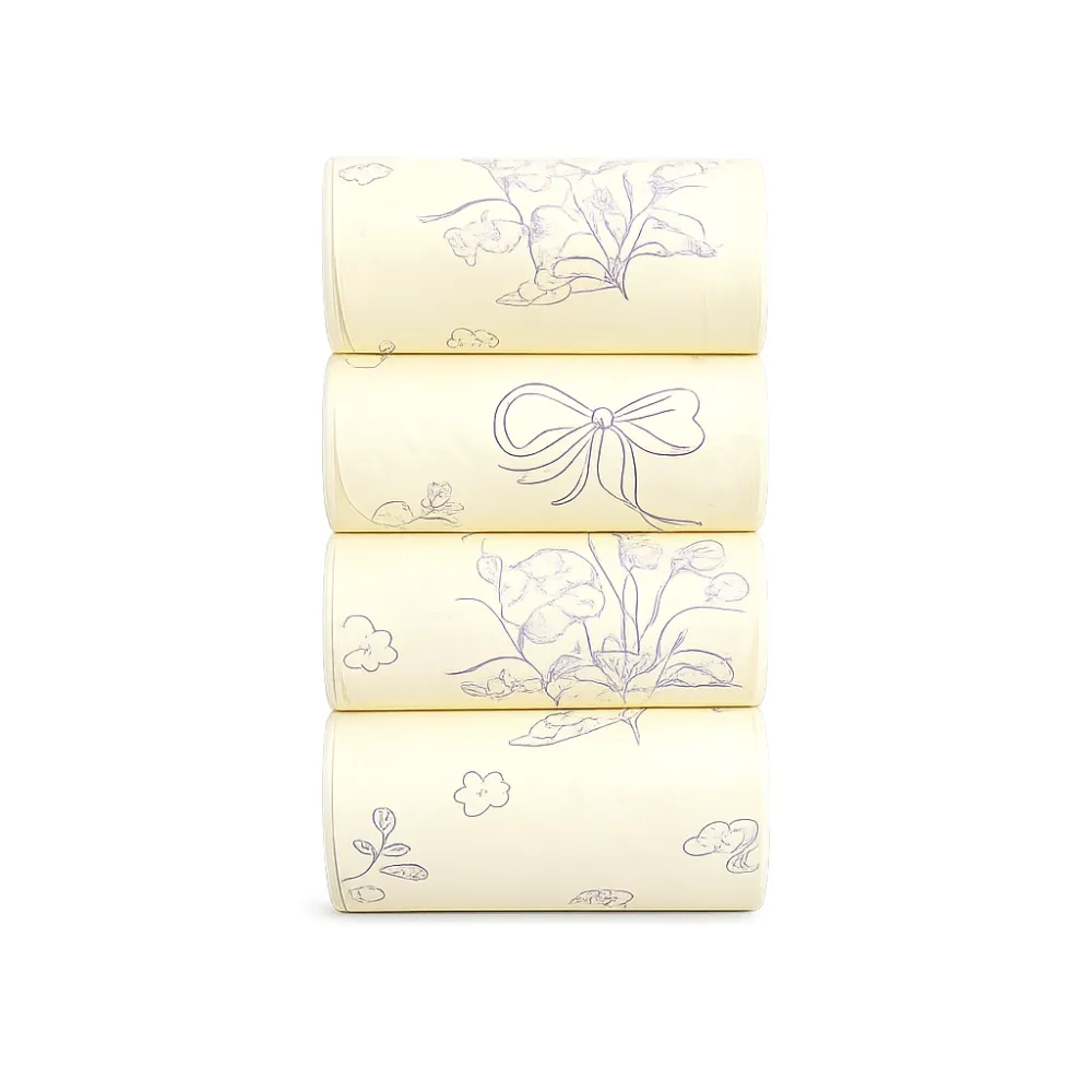 Close-up view of four rolls of light yellow scented dog poop bags decorated with purple flower and bow outlines.